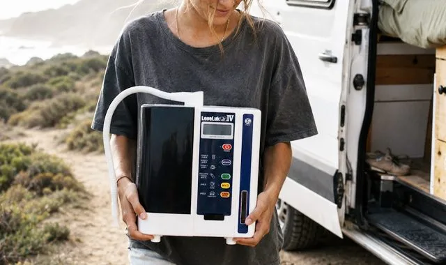 מטייל מחזיק את ה-LeveLuk JR IV הקומפקטי ליד קרוואן על חוף הים